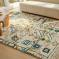Load image into Gallery viewer, A rectangular area rug with a Southwestern geometric pattern in blue, olive green, and black on a cream base, styled on a light wood floor in a bright living room next to a cream boucle sofa.